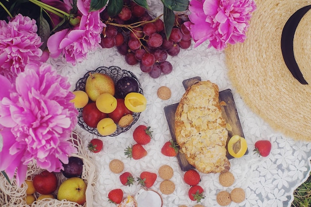 Piquenique de verão ao ar livre em estilo francês no jardim de peônia com croissant de amêndoa e frutas frescas