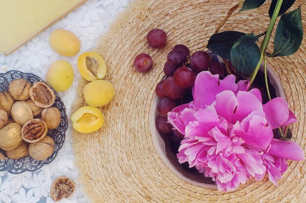 Piquenique de verão ao ar livre em estilo francês no jardim de peônia com croissant de amêndoa e frutas frescas