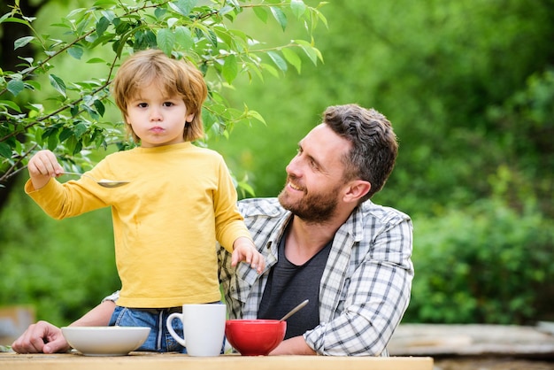 Piquenique de verão. Cafe da manha. Feliz dia dos pais. O garotinho com o pai come cereais. alimentação saudável e dieta. Dia das crianças. pai e filho comendo ao ar livre. hora do jantar em família. Aproveitando o tempo juntos.