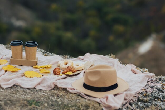 Piquenique na montanha com croissants frios de rosquinhas e chapéu