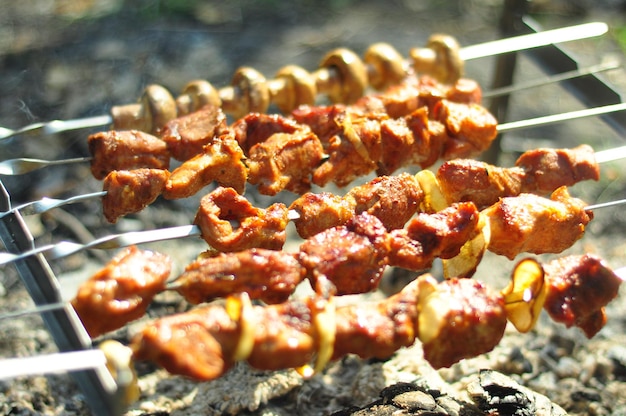 Piquenique na natureza cozinhando carne e cogumelos na brasa e fumando na fumaça suculenta carne apetitosa