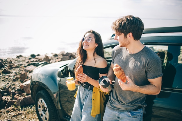 Piquenique perto da água. família feliz em uma viagem de carro. o homem e a mulher estão viajando pelo mar ou pelo oceano ou pelo rio. passeio de verão de automóvel. eles pararam para um lanche.