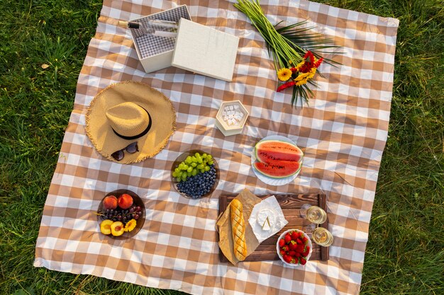 Piquenique romântico na natureza. A beleza do sol poente, frutas frescas e vinho.