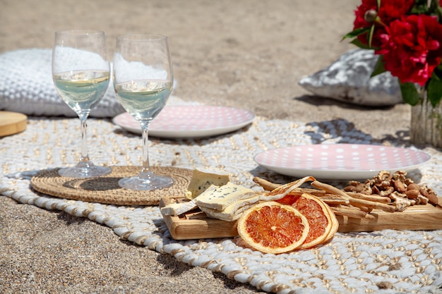 Piquenique romântico na praia com champanhe, lanches e flores. Conceito de férias e romance.