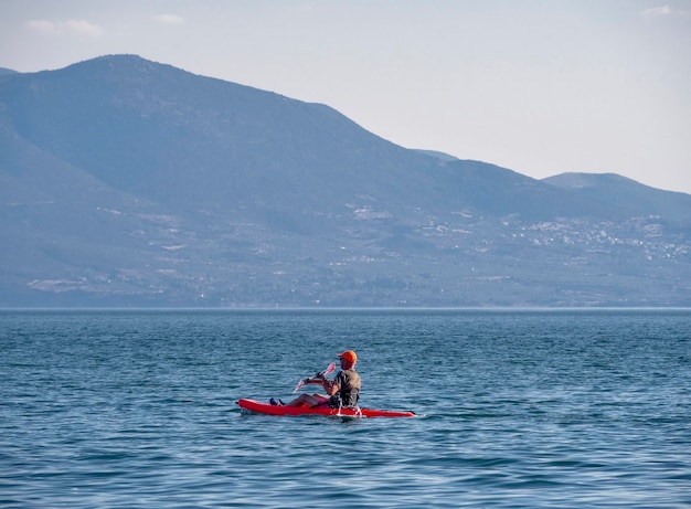 Los piragüistas van en canoa por el mar Egeo sobre el fondo de un acantilado en Grecia en un día soleado