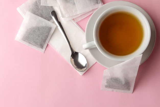 Pirámide de bolsita de té y taza con té sobre un delicado fondo rosa. para hacer té.