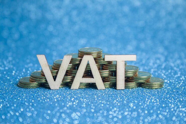 Foto pirámide compuesta por pilas de monedas de oro sobre un fondo azul y las palabras vat