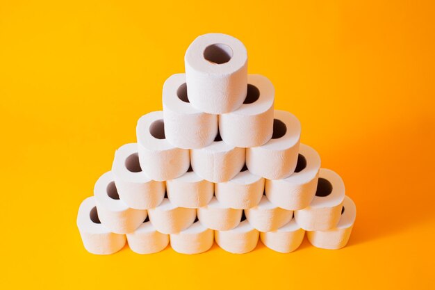 Pirámide creada a partir de rollos de papel higiénico blanco aislado en amarillo Símbolo de cuarentena