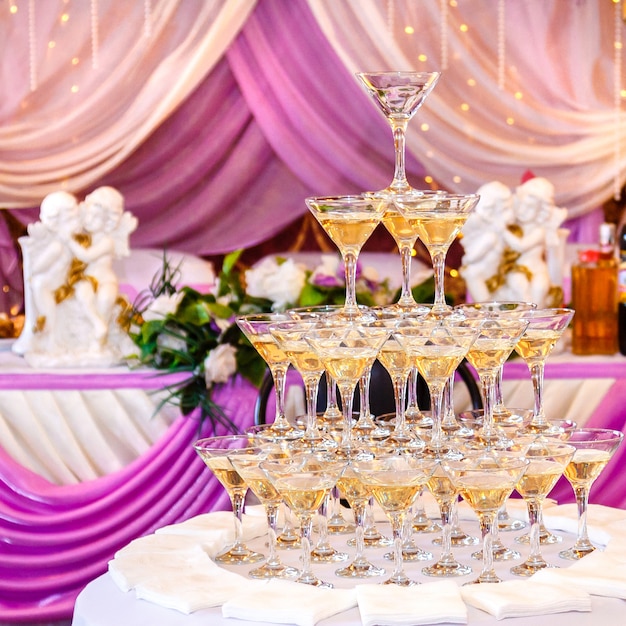 Pirâmide de copos com champanhe no interior do casamento roxo.