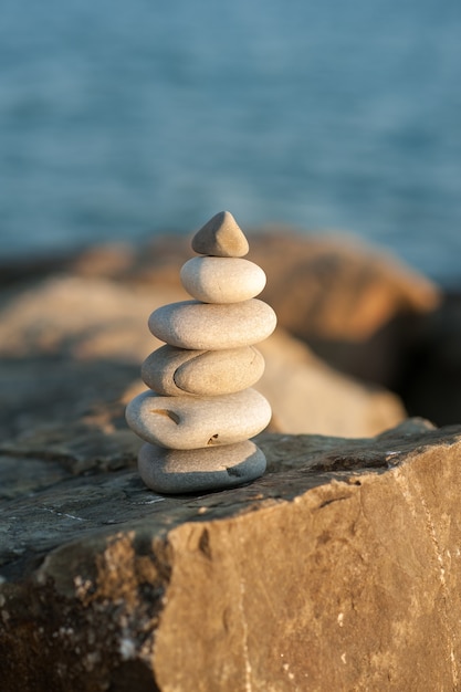 Pirâmide de pedra zen à beira-mar no sol poente