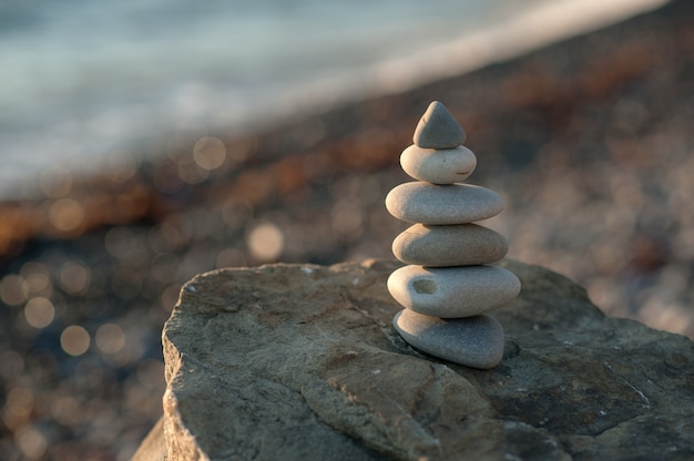 Pirâmide de pedra zen à beira-mar no sol poente