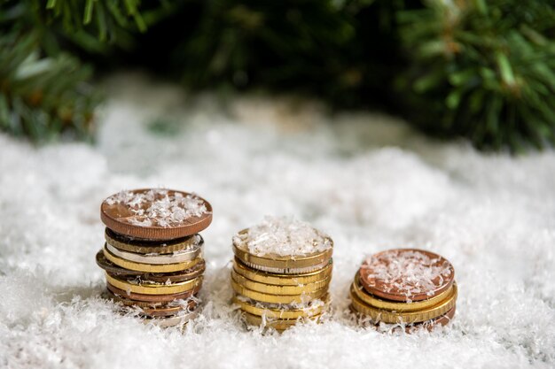 Una pirámide dorada de monedas cubiertas de nieve sobre un fondo de ramas de abeto verde. Concepto de éxito.