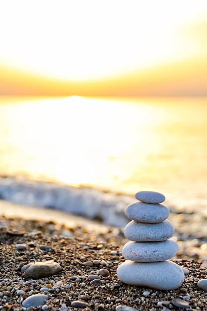 Foto pirámide de piedra tipo zen en la playa al amanecer