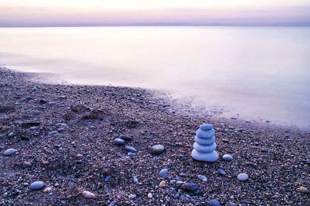 Pirámide de piedra tipo zen en la playa al amanecer