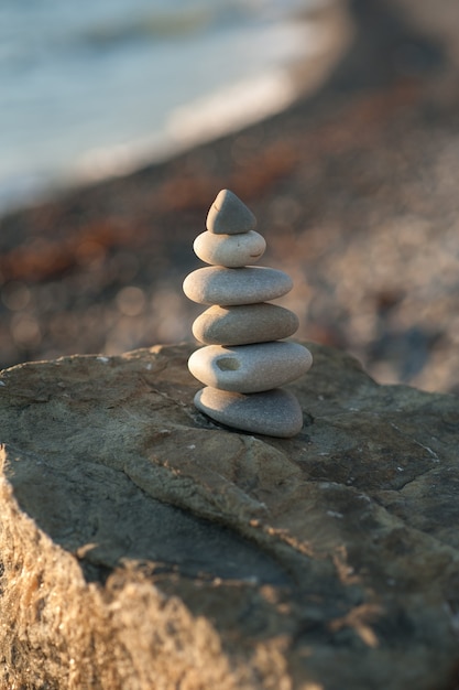 Pirámide de piedra zen en la orilla del mar en la puesta de sol