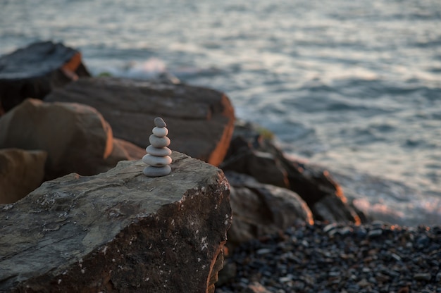 Pirámide de piedra zen en la orilla del mar en la puesta de sol