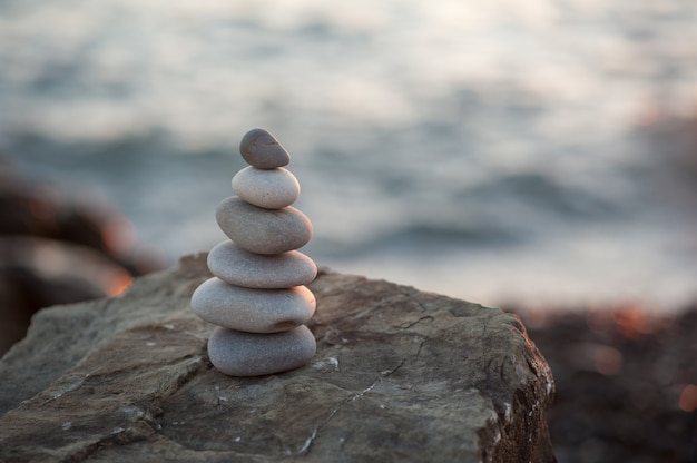 Pirámide de piedra zen en la orilla del mar en la puesta de sol