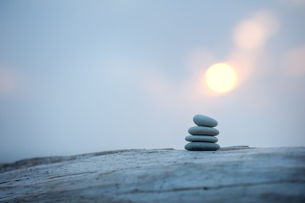 Foto pirámide de piedras junto al mar al amanecer. piedras zen equilibradas.