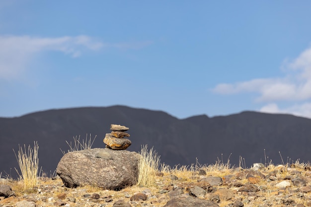 Una pirámide de piedras en las montañas contra el cielo azul el equilibrio de la meditación de piedras