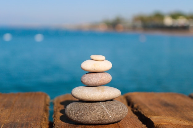 Pirámide de piedras en un muelle de madera por el mar concepto zen