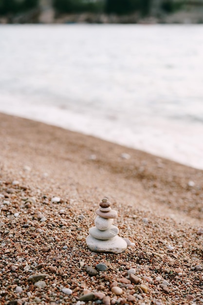 Pirámide de piedras en una playa de guijarros por el agua