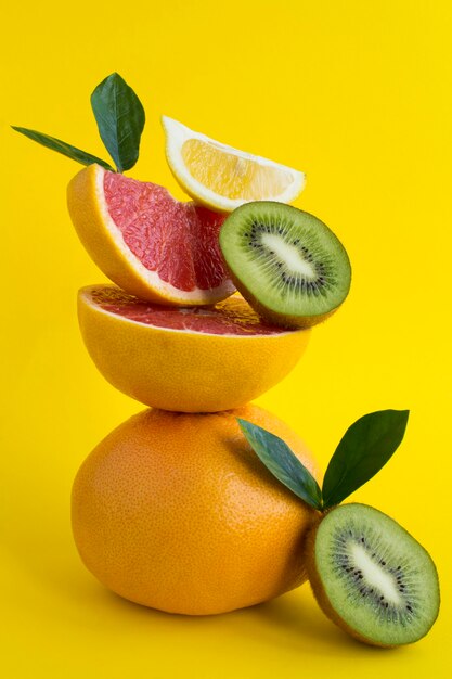 Pirámide de pomelo, kiwi y limón en equilibrio sobre el fondo amarillo. Primer plano. Ubicación vertical.