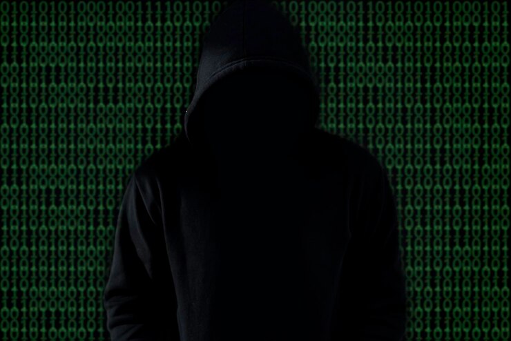 Foto pirata informático asiático con capucha negra sobre fondo negrohackear sistemas de seguridad de piratería de contraseñas para robar información