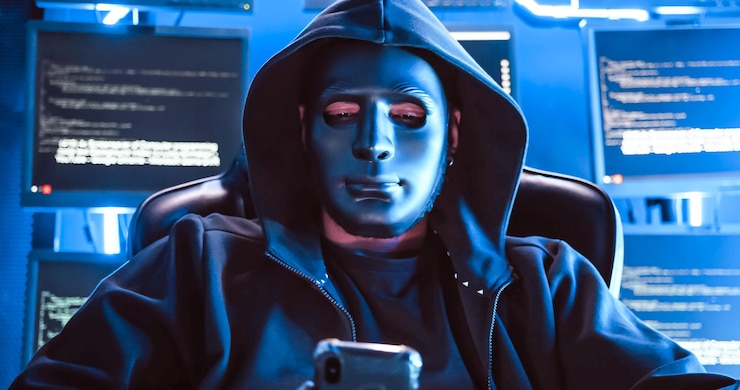 Foto un pirata informático que usa una máscara para cubrir su rostro está usando una computadora para piratear datos y obtener un rescate de las víctimas