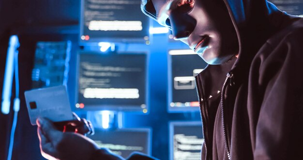 Un pirata informático que usa una máscara para cubrir su rostro está usando una computadora para piratear datos y obtener un rescate de las víctimas