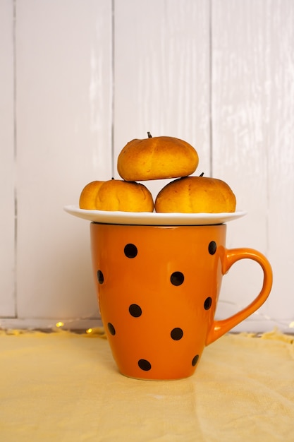 Pires com pequenos muffins em forma de abóbora em uma xícara de laranja