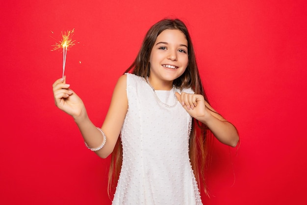 Foto pirotecnia y el concepto de la gente sonriendo mujer joven o adolescente mujer feliz con chispas celebrar en vestido blanco sobre fondo rojo