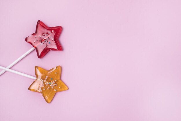 Piruleta en forma de estrellas rojas y amarillas sobre fondo rosa claro Caramelo de piruleta de fruta casera