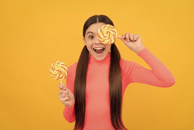 Piruleta niño niño con cabello largo sostenga piruleta caramelo de azúcar en la tienda de dulces de caramelo de palo