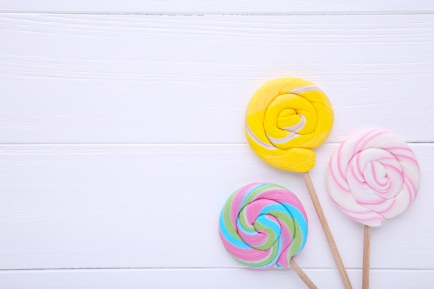 Piruletas de colores sobre fondo blanco de madera, dulces