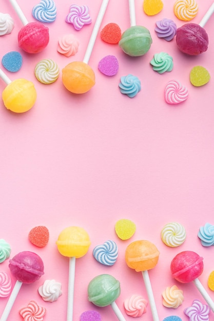 Piruletas dulces y caramelos sobre fondo rosa