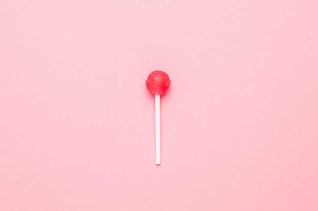 Pirulito cor-de-rosa doce dos doces no rosa pastel. Composição minimalista.