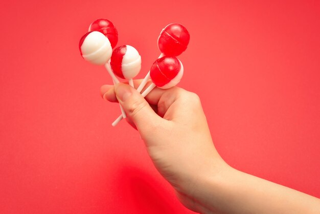 Pirulito na mão feminina sobre fundo vermelho. espaço para texto ou design.