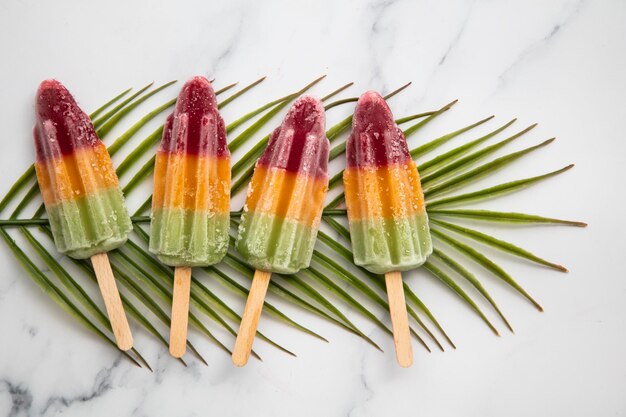 Pirulitos de frutas de verão em uma folha de palmeira tropical