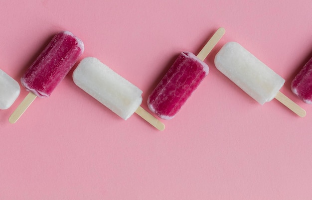 Pirulitos de gelo de verão rosa e branco em um fundo rosa