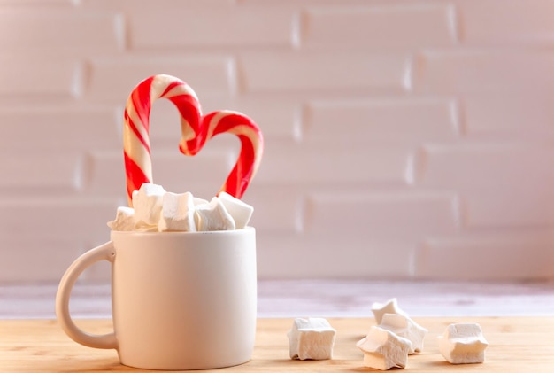 Pirulitos e marshmallows em uma caneca branca com doces de Natal xadrez em uma caneca Composição simples