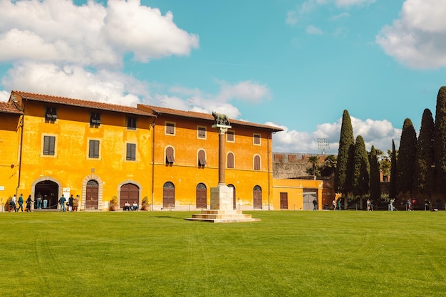 Pisa Italien 18. März 2023 Palazzo dell39Opernpalast Angelo Caduto Statue Lupa capitolina Denkmal auf Platz mit grünem Gras Rasen blauer Himmel weiße Wolken Hintergrund an sonnigen Tagen Toskana