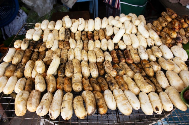 Pisang Awak ou bananas cultivadas grelhadas assadas com mel de casaco no fogão a carvão local para venda tailandês e viajantes estrangeiros no mercado retro vintage antigo baan madua em Nong Bua Lamphu Tailândia