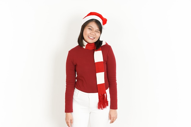 Foto piscadela e sorriso da bela mulher asiática usando gola alta vermelha e chapéu de papai noel isolado no branco