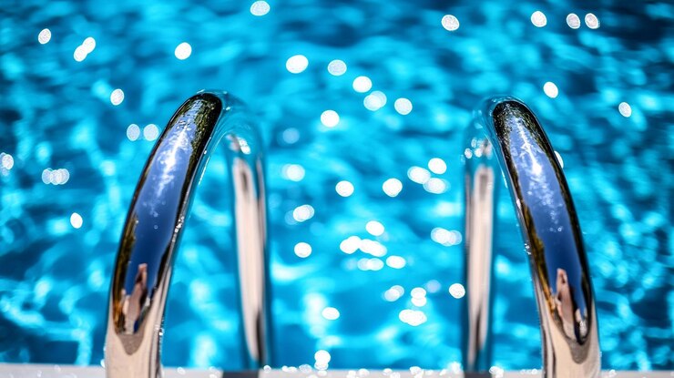 Foto piscina azul brilhante com um corrimão de aço inoxidável brilha sob a luz do sol a água