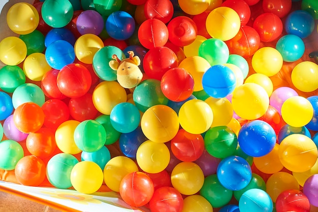 Una piscina de bolas con un lindo animal de peluche asomándose, se destaca del resto, concepto de diversidad.