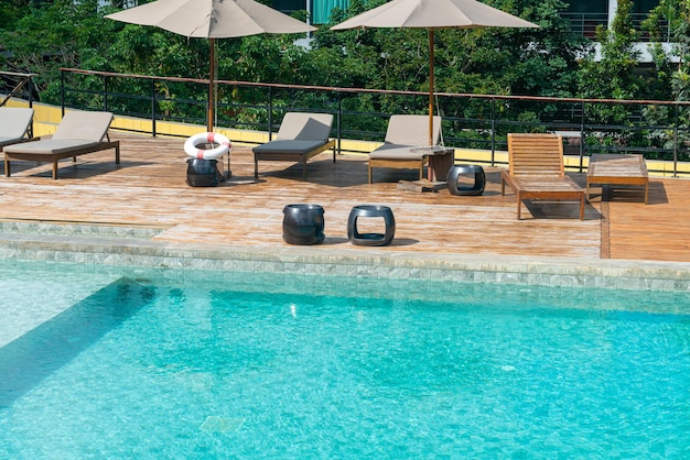 Piscina de cama con sombrilla alrededor de la piscina con fondo de cielo azul y montaña