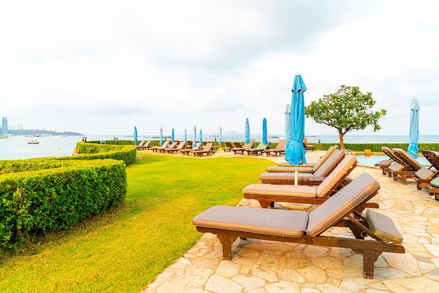 Piscina com cadeiras ou piscina com cama e guarda-sol ao redor da piscina com fundo de praia do mar em Pattaya, na Tailândia