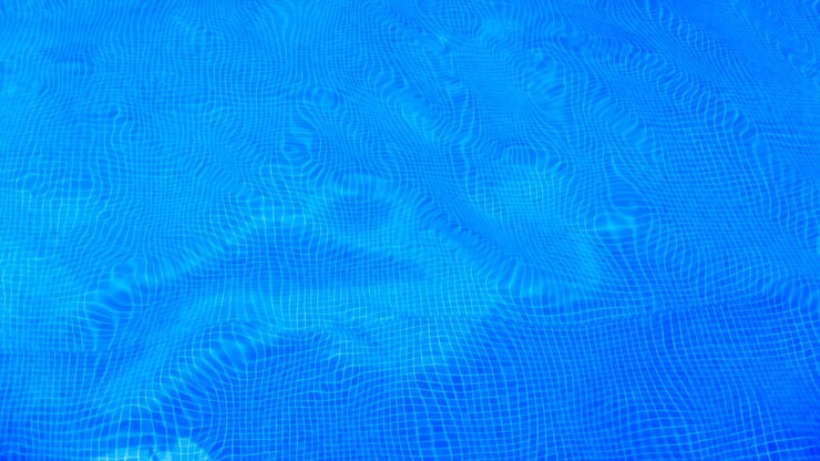 Foto piscina com fundo de água azul pura panorama do fundo da piscina com padrão de ladrilhos e superfície de ondulação de água