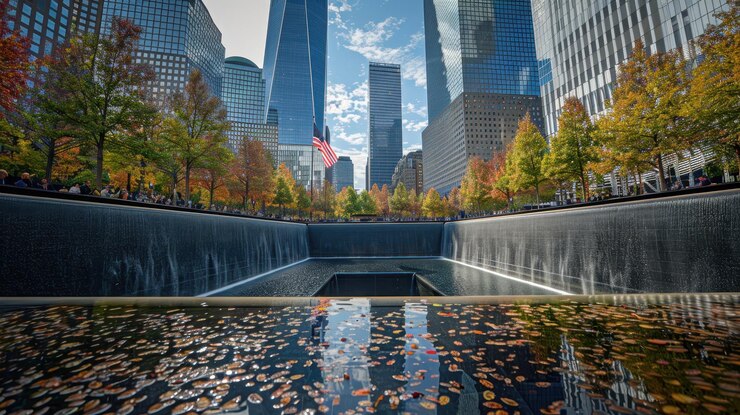 Una piscina conmemorativa reflectante rodeada de árboles de otoño y rascacielos de la ciudad que crean una serena