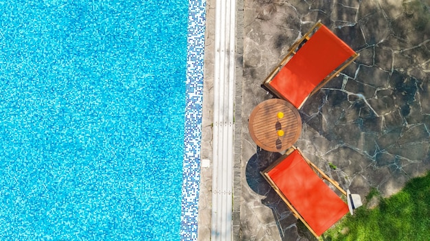 Piscina de água azul e espreguiçadeiras com vista aérea de topo hotel resort tropical de férias